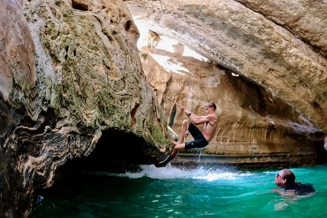 Flo klettert am Wasserfall hoch im Wadi Shab