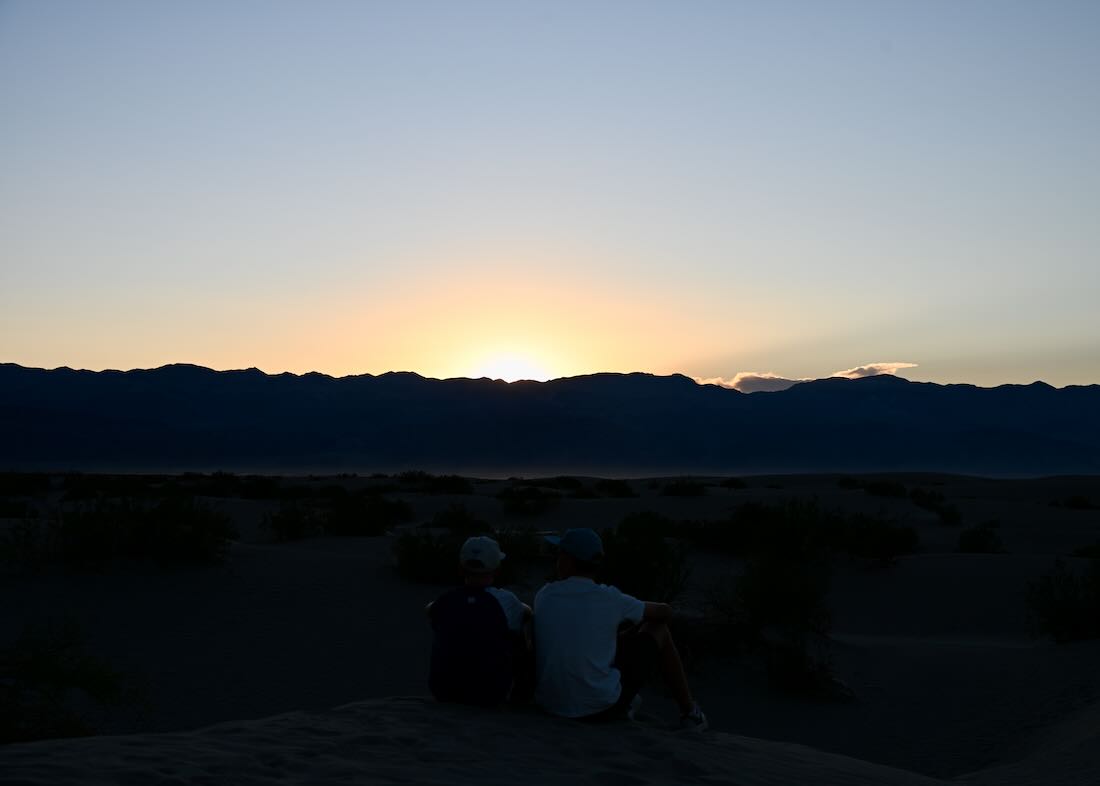 Flo und Ben sitzen in Mesquite Flat Sand Dunes bei Sonnenuntergang