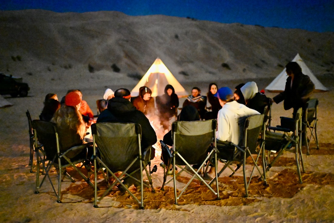 Die Reisegruppe Bonheur Voyages sitzt am Lagerfeuer in der Sahara